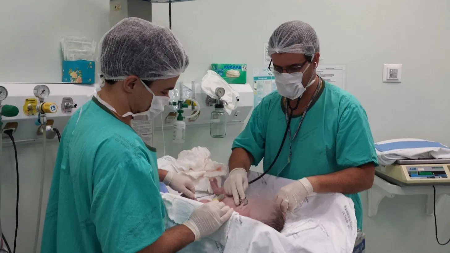 Eduardo do Nascimento Reis e seu pai, também pediatra, examinando um recém-nascido
